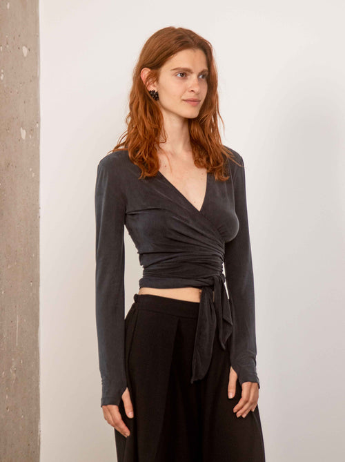 Model wearing the slate black cupro multiway wrap top with a fluid silhouette by Cossac